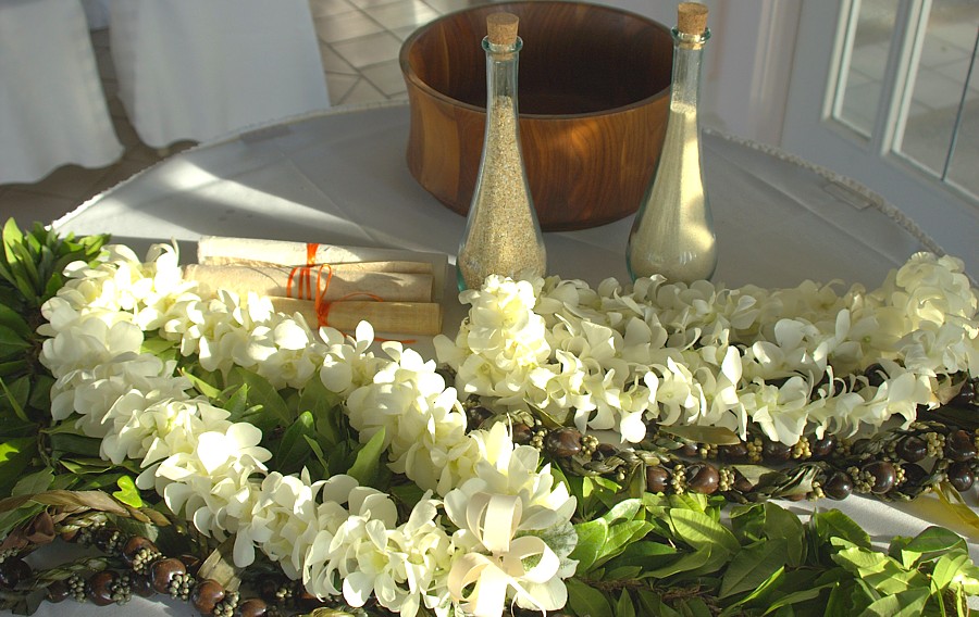 White orchid leis and sand ceremony vases on a table
